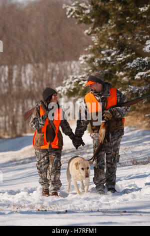 Männlichen und weiblichen Fasan Jäger im Winter mit gelben Labrador Stockfoto