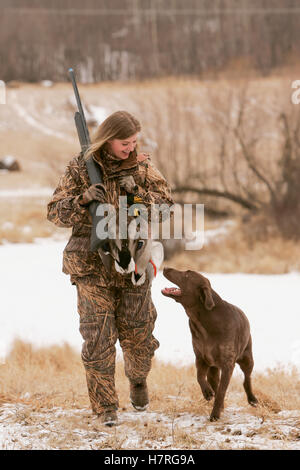 Weibliche Wasservögel Jäger mit Gewehr und Rusty Yellow Lab Stockfoto