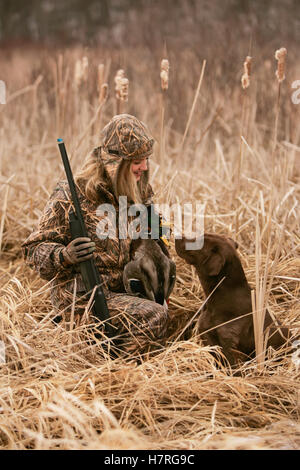 Weibliche Wasservögel Jäger mit Gewehr und Rusty Yellow Lab Stockfoto