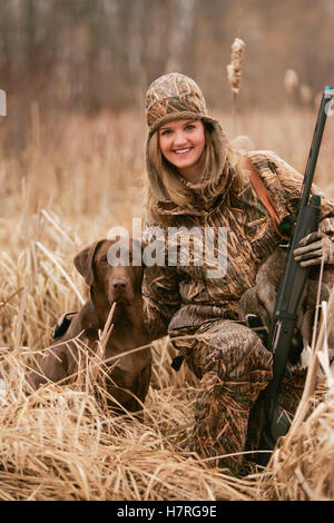 Weibliche Wasservögel Jäger mit Gewehr und Rusty Yellow Lab Stockfoto