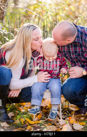 Ein junges Paar küsst ihren kleinen Sohn Kopf während er Swirms entfernt während Familienportraits im Herbst; Surrey, British Columbia, Kanada Stockfoto