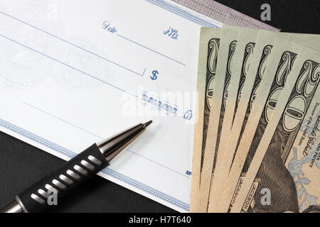 Stift auf Blanko-Scheck. Einige zwanzig-Dollar-Scheine sind neben den check.book Stockfoto