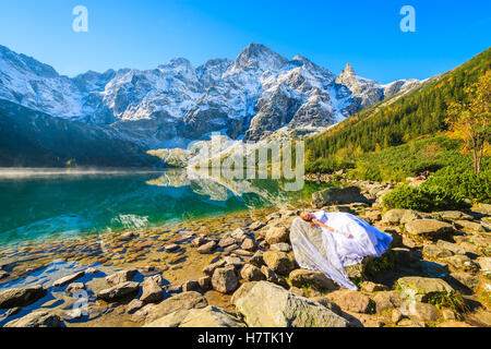 MORSKIE OKO LAKE, TATRA-Gebirge - SEP 24, 2016: junge Braut im weißen Kleid posiert auf Felsen beim Foto-Shooting bei Morskie Oko la Stockfoto