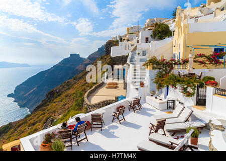 Paar von unbekannten Menschen entspannen auf der Terrasse eines Hotels in Firostefani Dorf mit typisch griechischen weißen Architektur, Santorin, Griechenland Stockfoto