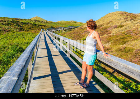 Junge Frau touristischen stehend auf Holzsteg zum Strand in Wenningstedt, Insel Sylt, Deutschland Stockfoto