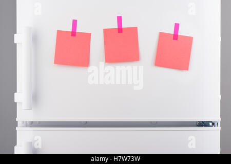 Drei leere rosa Papiernoten mit rosa Aufkleber auf weißen Kühlschranktür befestigt Stockfoto