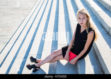 Blonde Frau sitzen auf Stufen bei Sonnenuntergang im Sommer Stockfoto