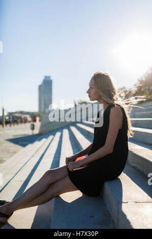 Blonde Frau sitzen auf Stufen bei Sonnenuntergang im Sommer Stockfoto