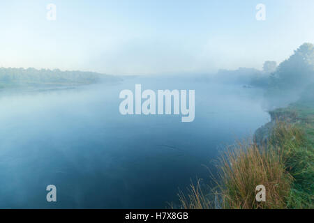 Nebel über dem Fluss. Herbstliche Morgennebel über den ruhigen Fluss führt in den Himmel bei Sonnenaufgang. Stockfoto