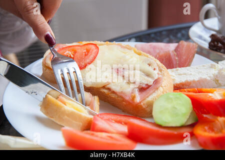 Leckeres Frühstück auf der Terrasse mit Sandwiches mit Schinken und Käse Kaffee und frischem Gemüse. Stockfoto