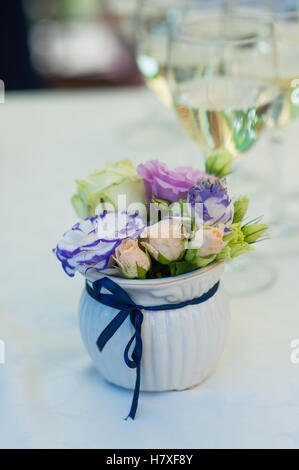 Blumenstrauß in Vase und zwei Gläser Champagner auf Tisch Stockfoto