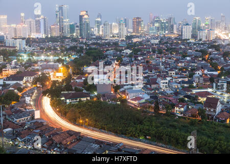 Sonnenuntergang über eine stark befahrene Straße führt zu hellen Geschäftsviertel von Jakarta in Indonesien Hauptstadt. Stockfoto