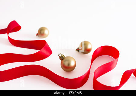Goldene Weihnachtskugel mit rotem Band auf weißem Hintergrund. Stockfoto