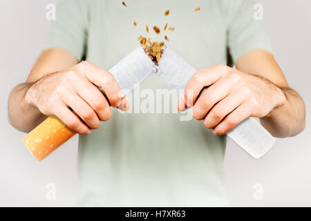 Aufhören zu rauchen - männliche Raucher brechen riesige Zigarette Stockfoto