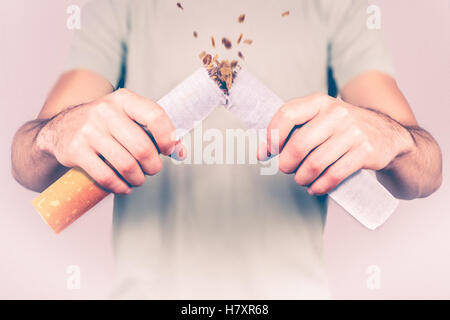 Aufhören zu rauchen - männliche Raucher brechen riesige Zigarette Stockfoto