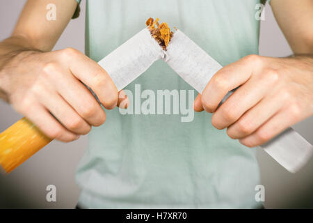 Aufhören zu rauchen - männliche Raucher brechen riesige Zigarette Stockfoto