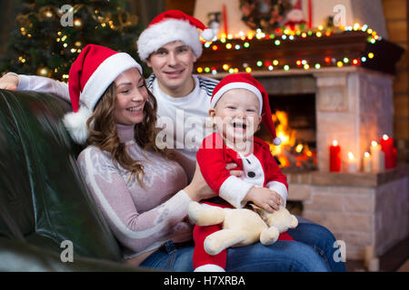 Glückliche Familie sitzen auf der Couch vor dem Kamin in festliche Weihnachts-Zimmer Stockfoto