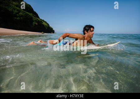 Richtungskontrolle Blick des jungen Mannes Wasser Surfen im Ozean. Männliche Surfer im Wasser des Meeres mit Surfbrett. Stockfoto