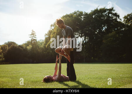 Flexibel und stark junges Paar Acroyoga im Freien zu tun. Mann und Frau im Park paar Yoga-Übungen praktizieren. Stockfoto