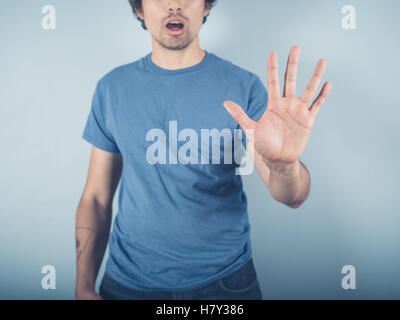 Ein junger Mann trug ein blaues T-shirt hebt seine offene Hand um Stop-signal Stockfoto