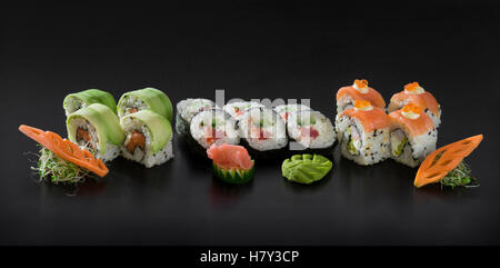Frisches Sushi gesetzt. Uramaki und Kombu Sushi-Rollen auf schwarzem Hintergrund Stockfoto