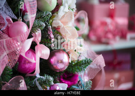 Ein Weihnachtsbaum voll behängt mit Weihnachtsschmuck. Im Hintergrund Kind Spielzeug, das verschwindet in der Unschärfe Stockfoto
