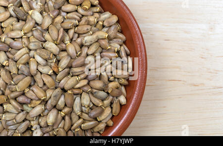 Enge Draufsicht einer kleinen Schüssel gefüllt mit Bio-Milch Distel Samen auf einem Holztisch. Stockfoto
