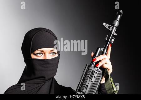Muslimische Frau mit einem Maschinengewehr. Eine bewaffnete Frau schießt. Islamische Frau mit einer automatischen Waffe. Konzept von Krieg und Terrorismus Stockfoto