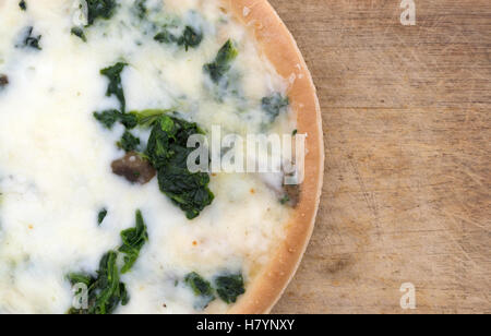 Enge Draufsicht einer gekochten Spinat-Pilz-Pizza auf ein Holz Schneidebrett. Stockfoto