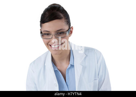 Ärztin, die lächelnd vor weißem Hintergrund Stockfoto