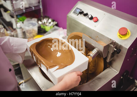 Mittleren Bereich des Arbeiters, die geschmolzene Schokolade Form einfüllen Stockfoto