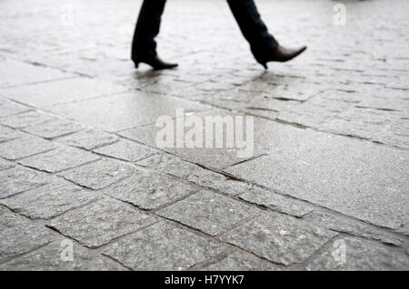 Nasse Füße mit spitzen Schuhen laufen auf Asphalt Stockfoto