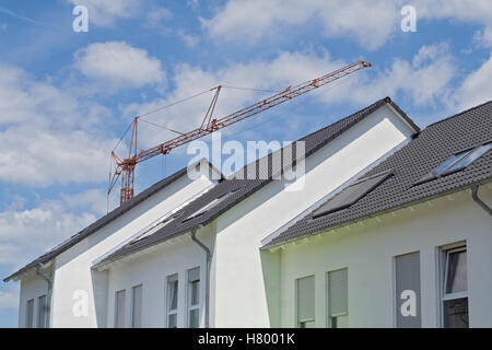 Dächer von drei Reihenhäuser neue mit Baukran Stockfoto