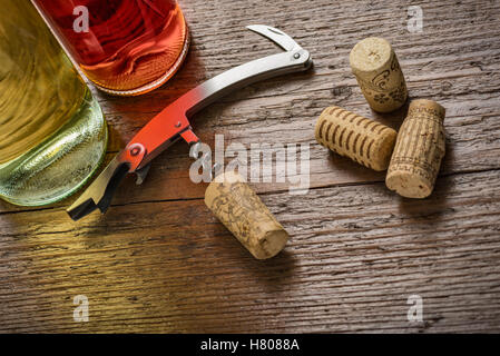 Korkenzieher mit eingefügt Kork und Weinflaschen auf Holztisch Stockfoto