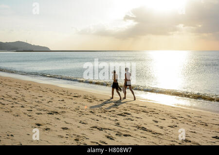 Älteres Paar zu Fuß am Strand und goldene schöne Himmelslicht reflektierenden am Ozean. Stockfoto