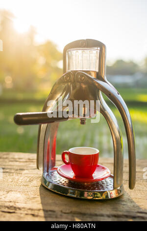 Manuelle Oldschool Espresso Maker Maschine mit einer Tasse auf Holztisch im schönen Morgenlicht Stockfoto
