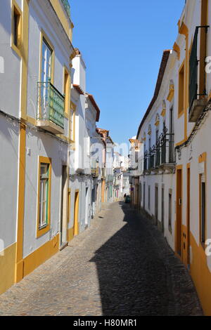 EVORA, PORTUGAL: typisch engen und gepflasterten Straße mit Häusern in weiß und gelb lackiert Stockfoto