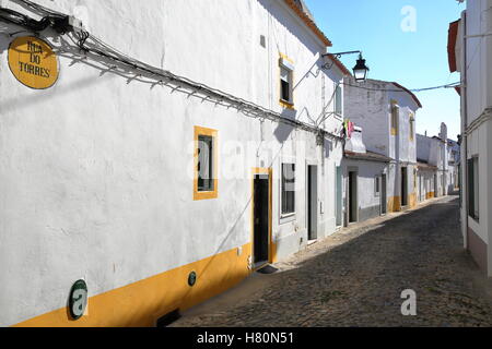 EVORA, PORTUGAL: typisch engen und gepflasterten Straße mit Häusern in weiß und gelb lackiert Stockfoto