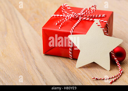 Einfache, klassische rote Weihnachtsgeschenk mit handgefertigten leer Geschenkanhänger auf rustikalen Holz horizontale Hintergrund präsent. Stockfoto