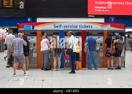 Bahnpassagiere an Selbstbedienungsfahrkartenautomaten am Bahnhof London Waterloo, London England Großbritannien Stockfoto