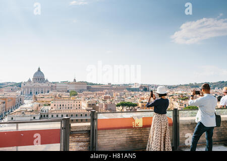 Eine männliche und eine weibliche Touristen fotografieren von Vatikanstadt & St. Peters Platz von Castel Sant'Angelo in Rom, Italien Stockfoto