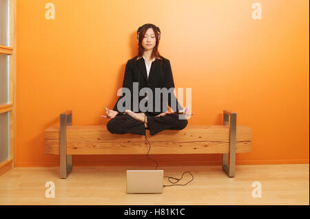 Frau im Lotussitz beim Musikhören entspannend Stockfoto