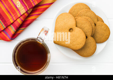 Lebkuchenherzen und Tasse Tee auf weißen Tisch. Ansicht von oben. Stockfoto
