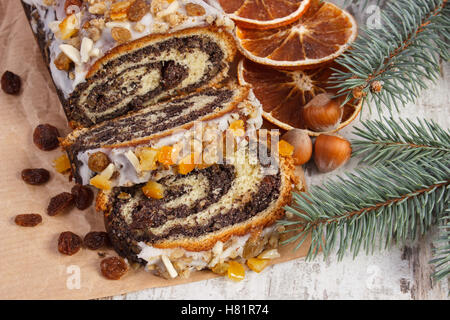 Hausgemachte Mohn Samen Kuchen und Fichte Zweige auf rustikalen Brett, Dessert und Dekoration für Weihnachten, traditionelle Polis aufgerollt Stockfoto