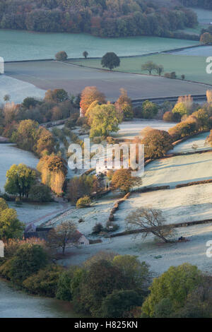 Haus und Ackerland in dem Tal von Downham Hügel von Uley Bury an einem kalten, frostigen Herbstmorgen kurz nach Sonnenaufgang. Gloucestershire, England Stockfoto