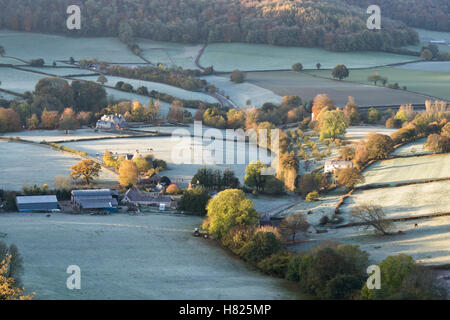 Haus und Ackerland in dem Tal von Downham Hügel von Uley Bury an einem kalten, frostigen Herbstmorgen kurz nach Sonnenaufgang. Gloucestershire, England Stockfoto