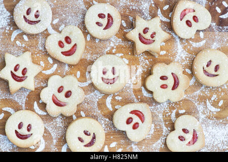 Hausgemachte Jammie Dodgers. Lächelndes Gesicht Kekse und Puderzucker Zucker Eindrücke auf Holz