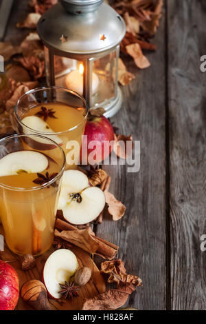 Heißer Apfelwein mit Zimtstangen und Gewürzen auf Herbst Blätter Hintergrund Stockfoto