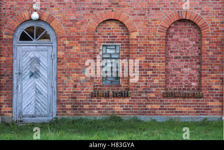 Bögen und Tür in eine Wand aus roten Ziegelsteinen. Stockfoto