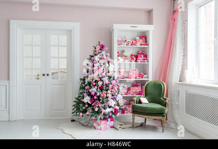 Schöne Ferienwohnung eingerichtete Zimmer mit Weihnachten Bäume, Regal und rosa blau Geschenke drauf, grünen Stuhl Wohngebäude Stockfoto